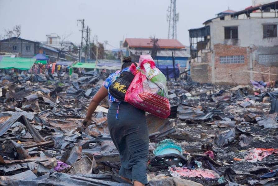 A woman collects scrap metal on a trash heap in Mandalay, Myanmar, that caught fire during the 2025 earthquake.