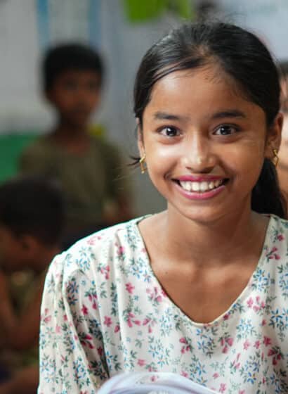 A girl sits and smiles during a lesson at a learning center in Kutupalong Refugee Camp in Bangladesh.