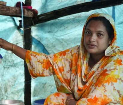 A woman fills a metal pitcher from a tap in her home that forms part of a safe water network in Kalishakhali village, Bangladesh.