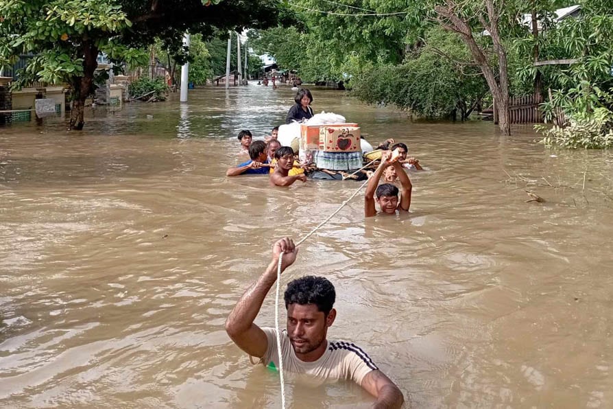 Shoulder deep in floodwater, people pull a raft carrying emergency supplies during the floods caused by Typhoon Yagi in Myanmar in September 2024.