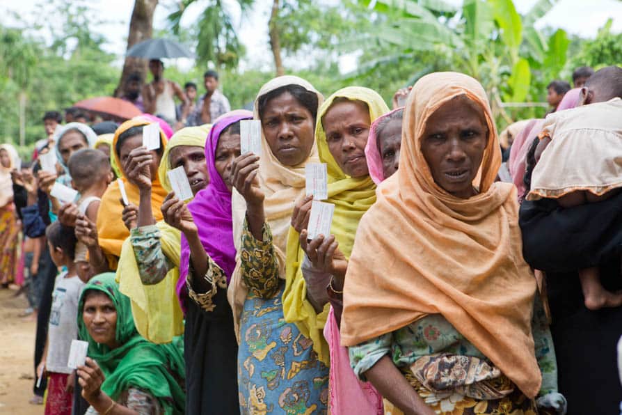 Women wearing headscarves wait in line to receive rations in Kutupalong Refugee Camp, Bangladesh.