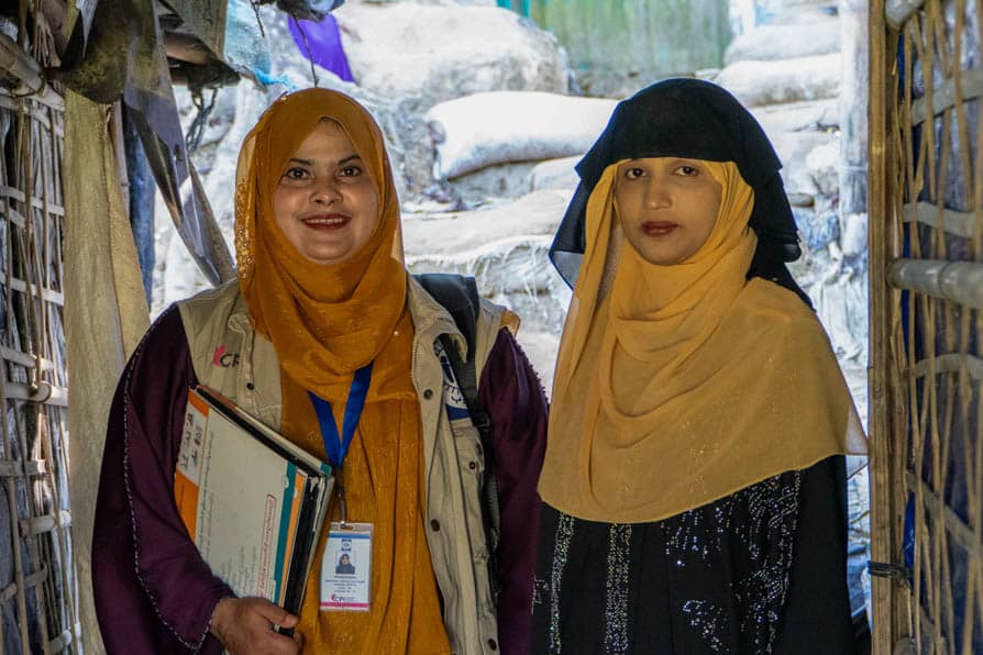 A Rohingya community health worker and a pregnant woman stand together in Kutupalong Refugee Camp in Bangladesh.