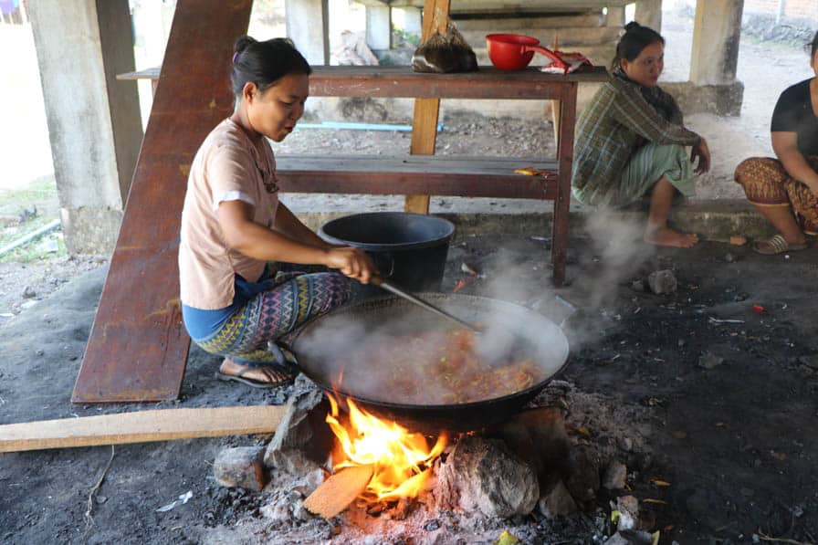 A woman stirs a large pot of food over an open fire at a school in southeastern Myanmar.