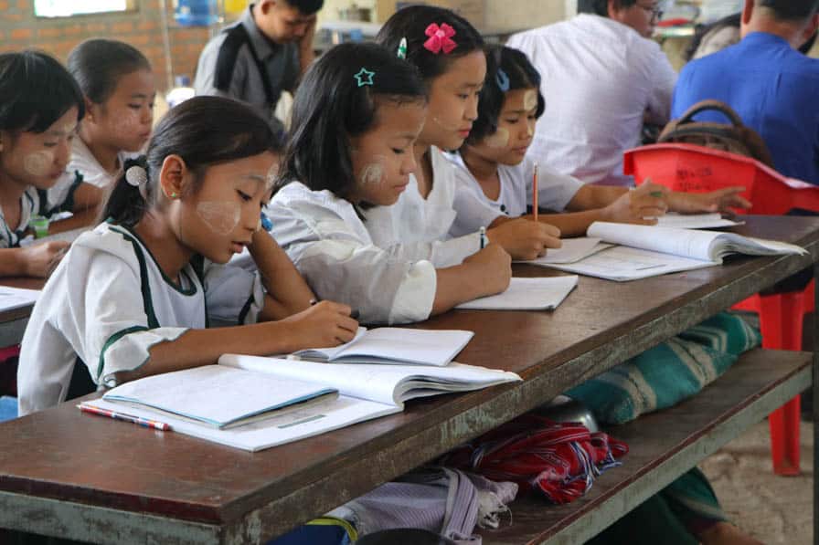 Children sit writing at their desks at a school in southeastern Myanmar.