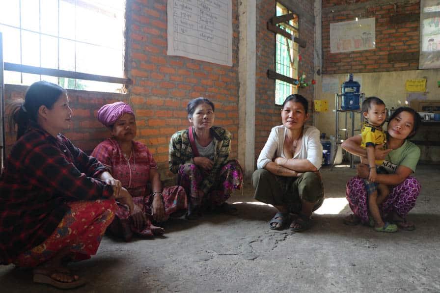 Five women participants of a community school meals initiative sit together in a school in southeastern Myanmar.