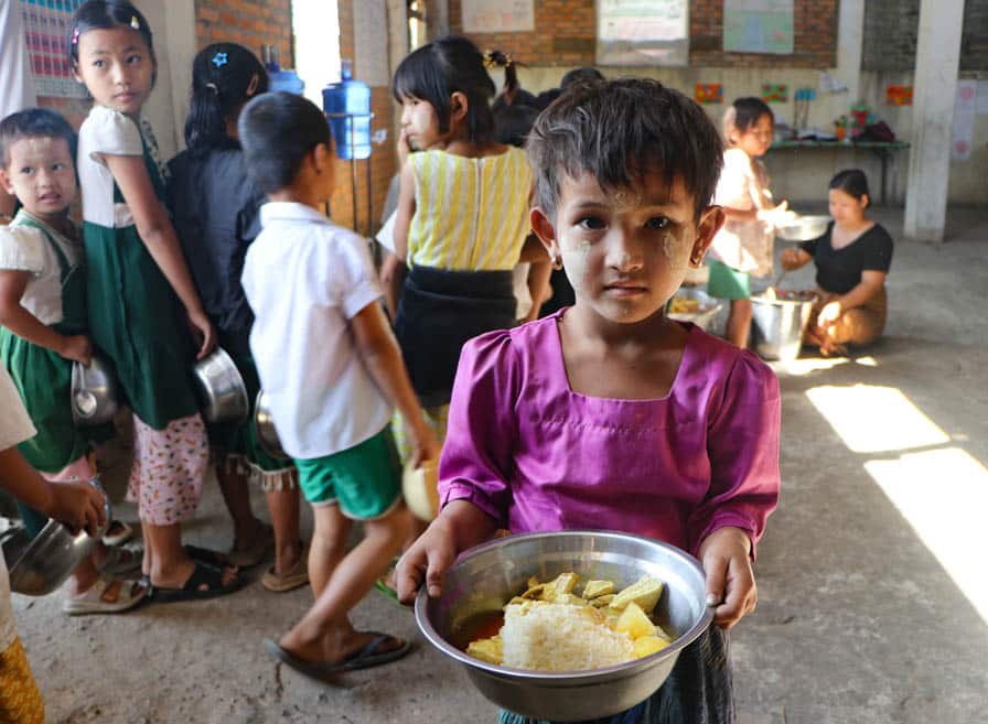 A girl holds a bowl of food prepared by community members at her school in southeastern Myanmar.
