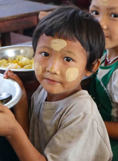 A girls sits with a meal prepared by community members at a school in southeastern Myanmar.