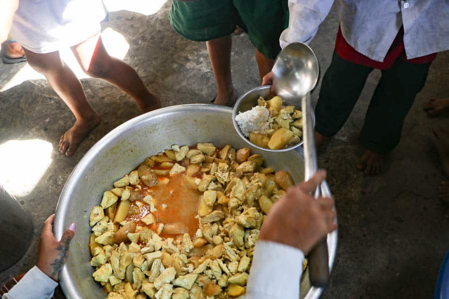 A child receives a meal cooked by community members at a school in southeastern Myanmar.