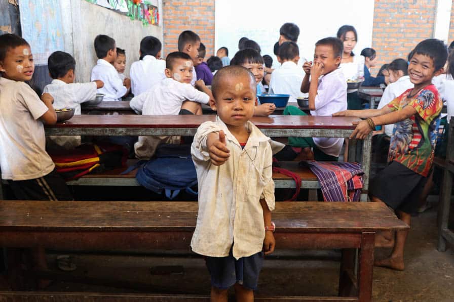 A boy stands in front of a classroom of his peers with his thumb raised at a school in southeastern Myanmar.