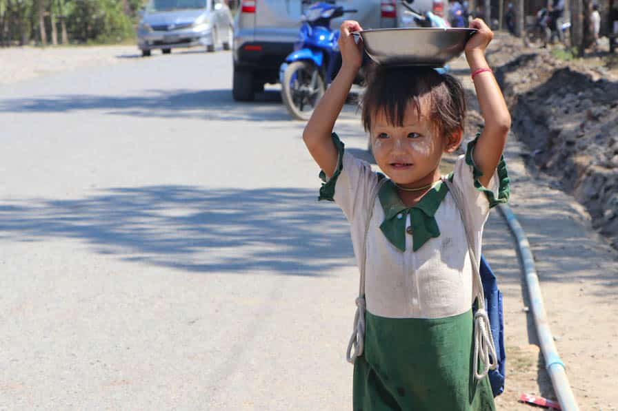 A young girl walks down a road in southeastern Myanmar carrying a bowl of food on her head cooked by community members at her school.