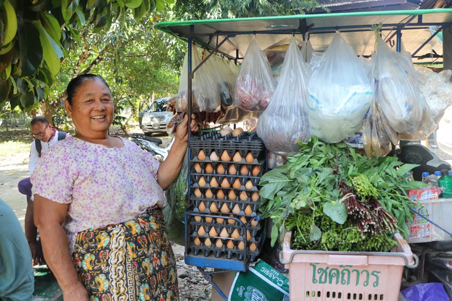 A vendor in southeastern Myanmar with a card laden with vegetables and eggs.