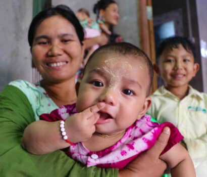 A baby girl is held in her mother's arms in a maternity waiting home in Myanmar