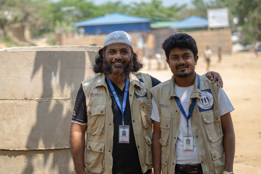 A WASH engineer and Rohingya WASH worker stand together in Kutpualong Refugee Camp, Bangladesh.