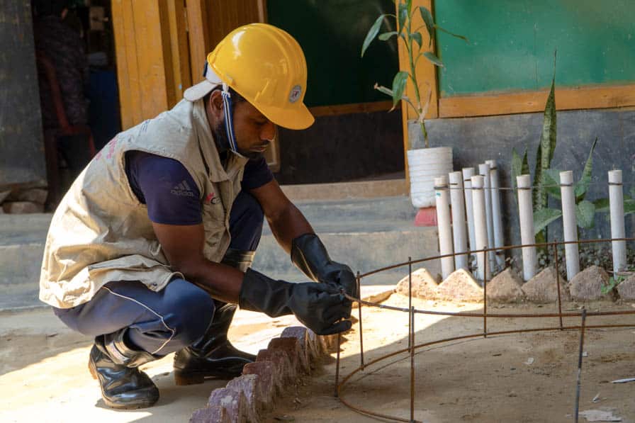 A Rohingya WASH worker prepares a steel rod frame to strengthen a concrete cesspit ring in Kutupalong Refugee Camp, Bangladesh.
