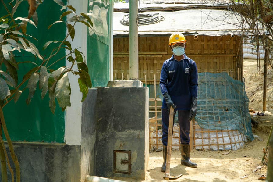 A Rohingya sanitation worker stands beside a toilet block with a menstrual hygiene management chamber in Kutupalong Refugee Camp, Bangladesh.