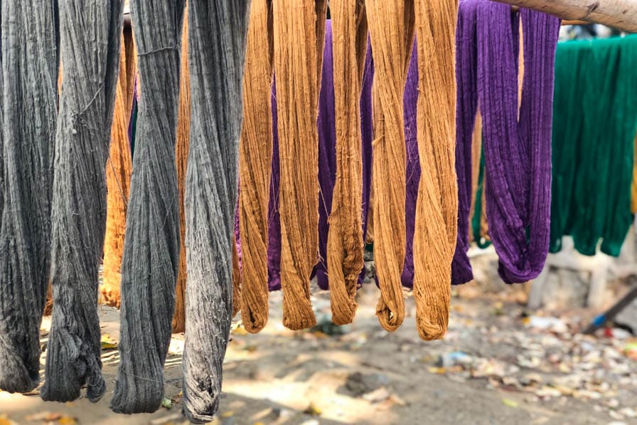 Lengths of colorful yarn hanging from bamboo poles in Amarapura, Myanmar.
