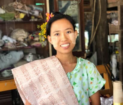 A handloom weaver with woven fabric over her shoulder in Amarapura, Myanmar.
