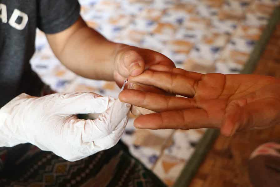 A community volunteer performs a finger prick as part of a malaria rapid diagnostic test in southeastern Myanmar.