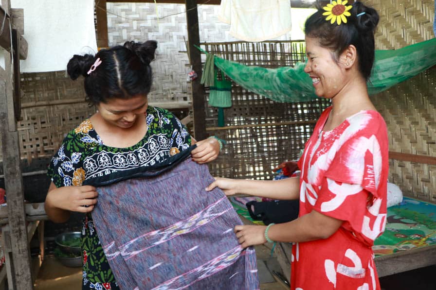 Daw Khin Myo Wai's two daughters examine fabric in their handloom weaving workshop in Amarapura, Myanmar.