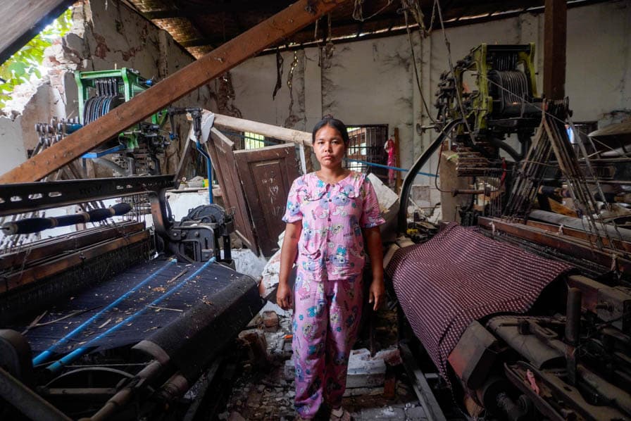A woman stands among damaged looms in a building in Amarapura, Myanmar, that partially collapsed during the March 2025 earthquake.